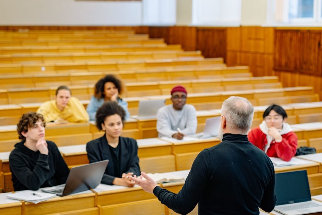 A group of adult students sitting in a lecture hall listening to a tutor