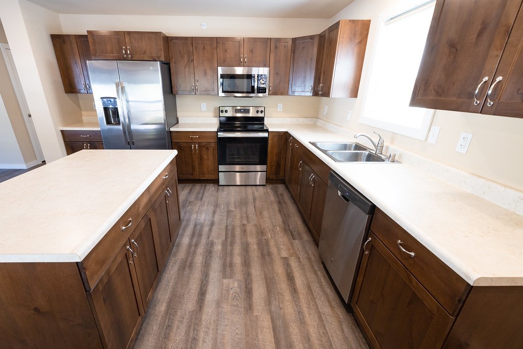 A modern empty apartment kitchen with wooden units, worktops and a built-in oven