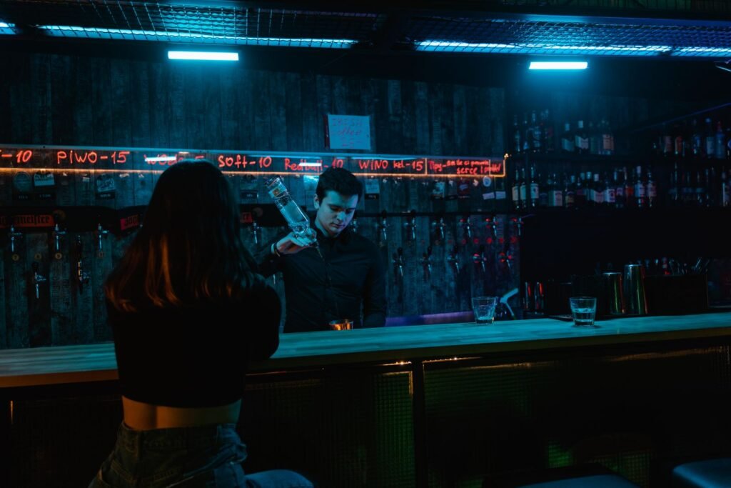A bartender pouring a drink under neon lights