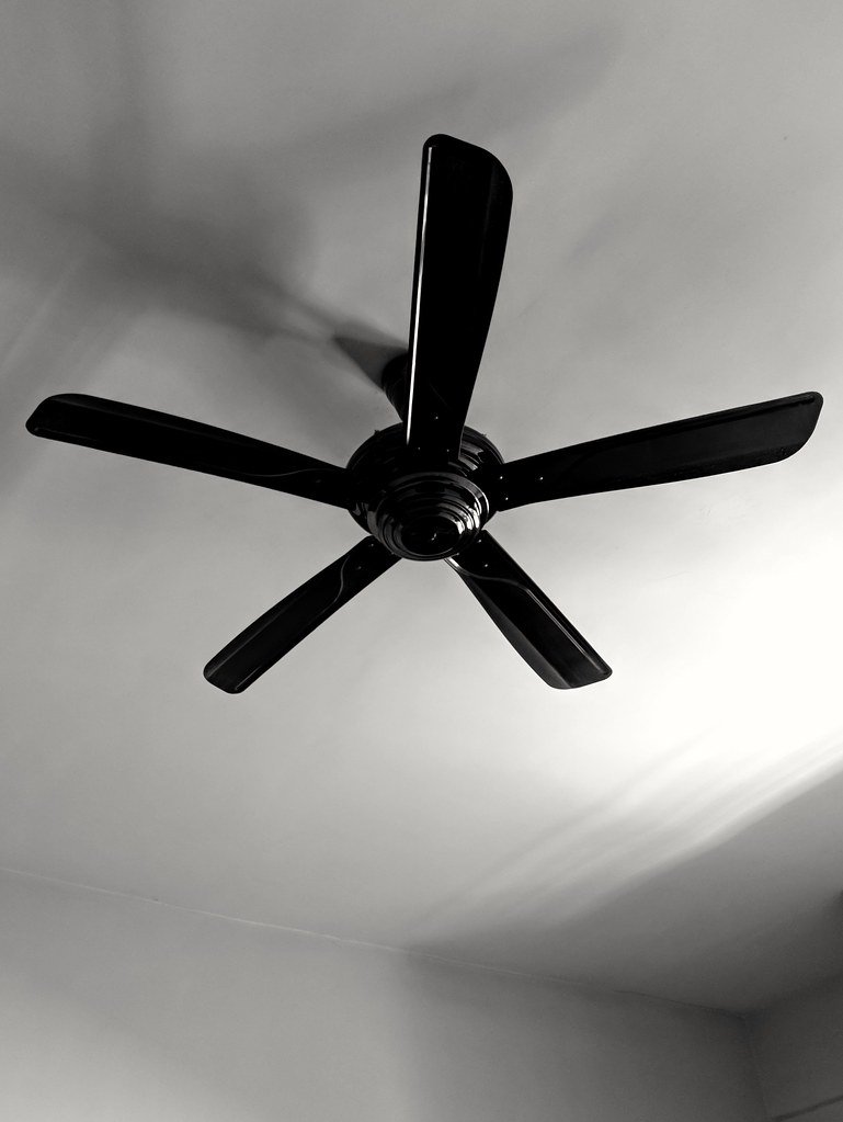 A black five-blade ceiling fan photographed from below against a white ceiling
