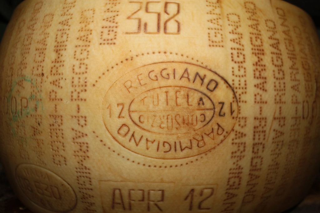 A large whole wheel of hard cheese with its rind stamped, filling the frame