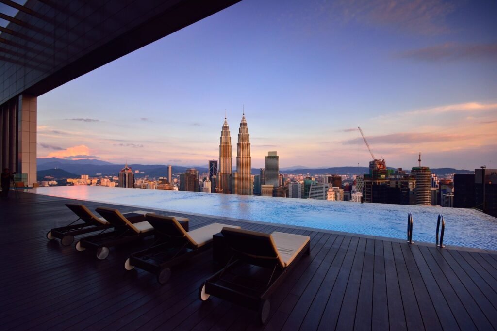 Sun loungers beside a rooftop infinity pool looking out over the Kuala Lumpur skyline