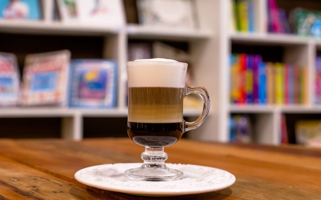 A layered iced coffee in a tall glass on a cafe table